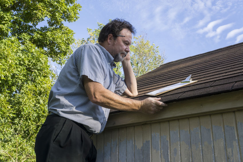 Insurance adjuster checking a roof for hail damage.