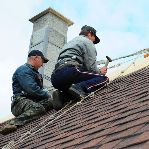 roof installation with two workers on asphalt roof