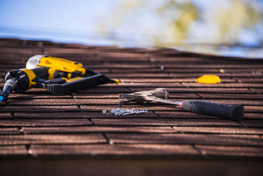 hammer, nails, and power screw driver on an asphalt roof