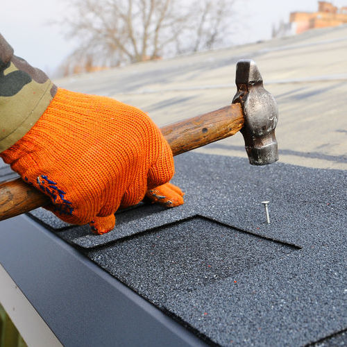 hammering a nail in asphalt shingle roof